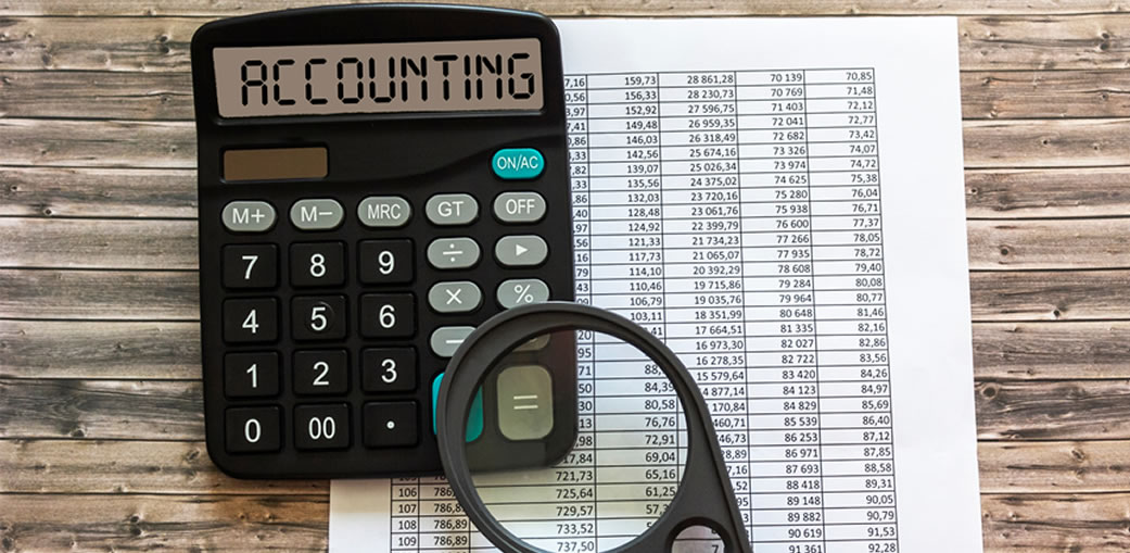 Calculadora e lupa sobre planilha, representando os benefícios econômicos da locação de equipamentos para construção civil.